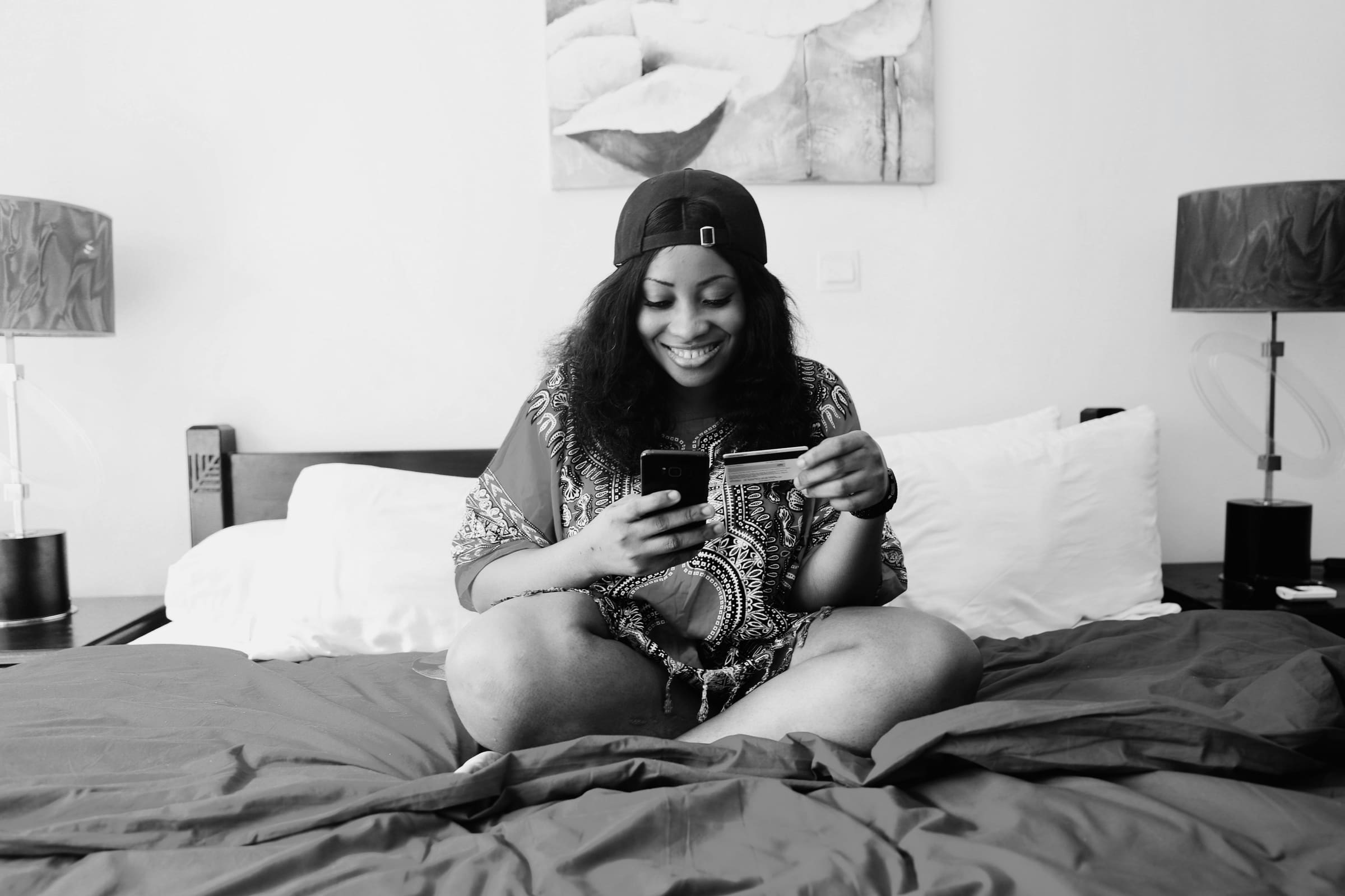 Sarah M. using a phone on a hotel bed